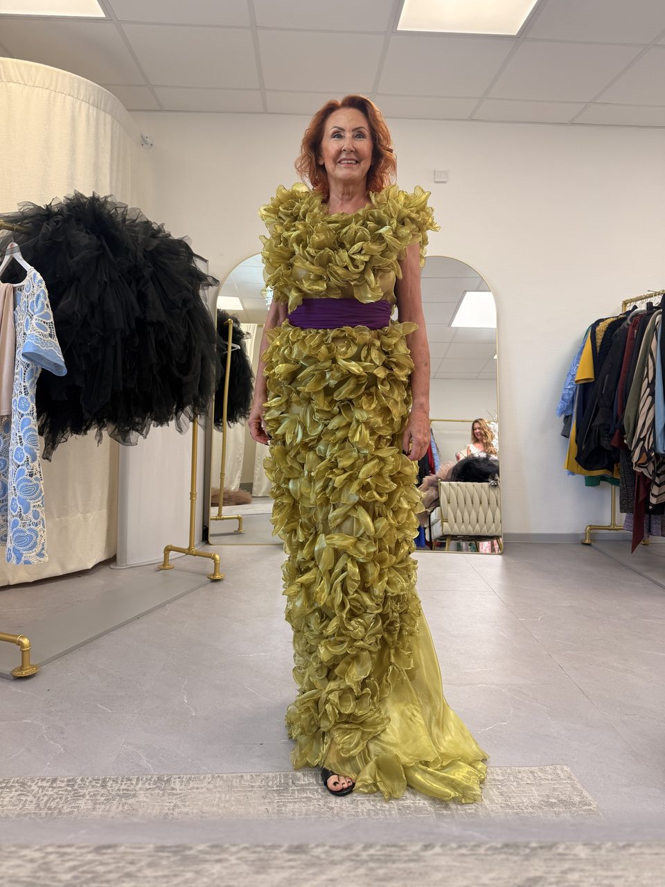 Marietta bei der Anprobe in einer olivgrünen Organza-Robe mit lila Schärpe