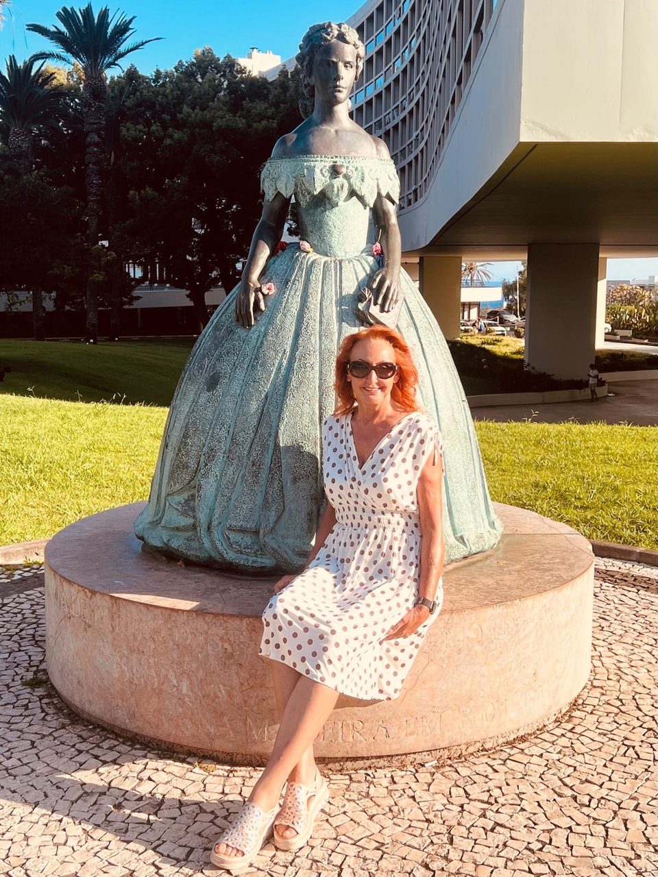 Marietta im weißen Punktekleid auf dem Sockel der Sissi-Statue in Funchal, Madeira